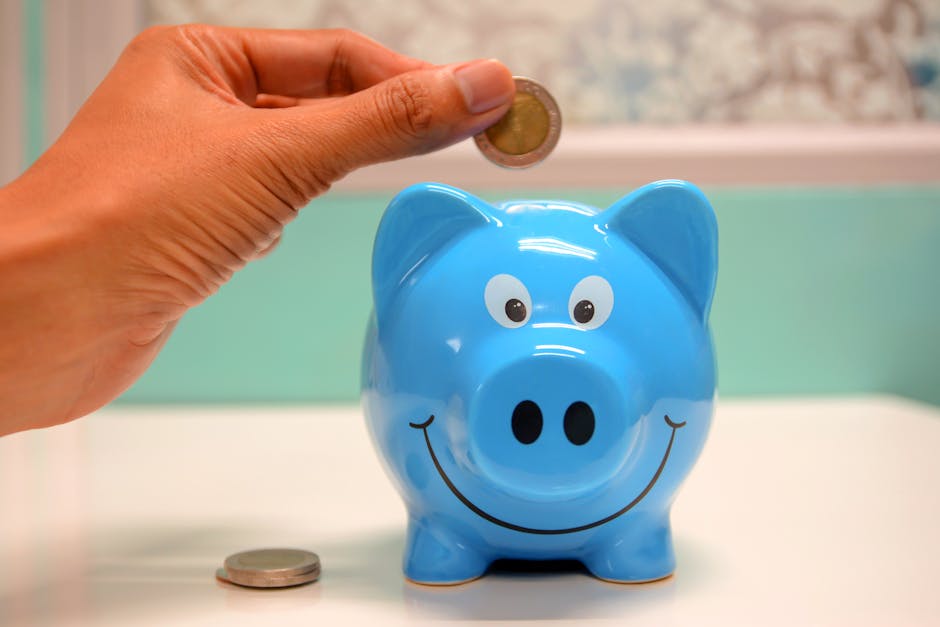 Hand inserting a coin into a blue piggy bank for savings and money management.